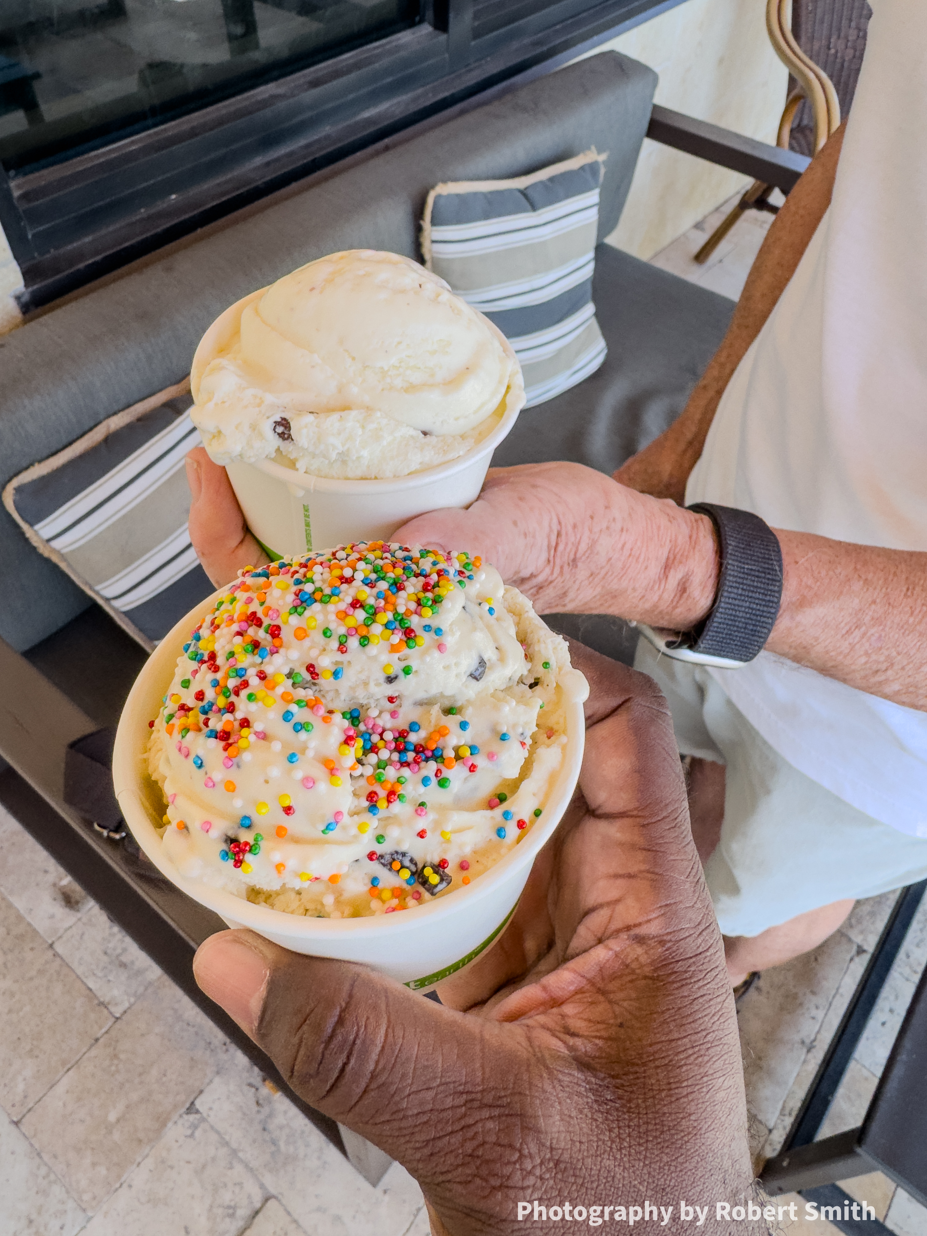 Two cups of ice cream held beside each other, Robert’s covered in multicolored sprinkles in the foreground and Neal’s without sprinkles behind it.